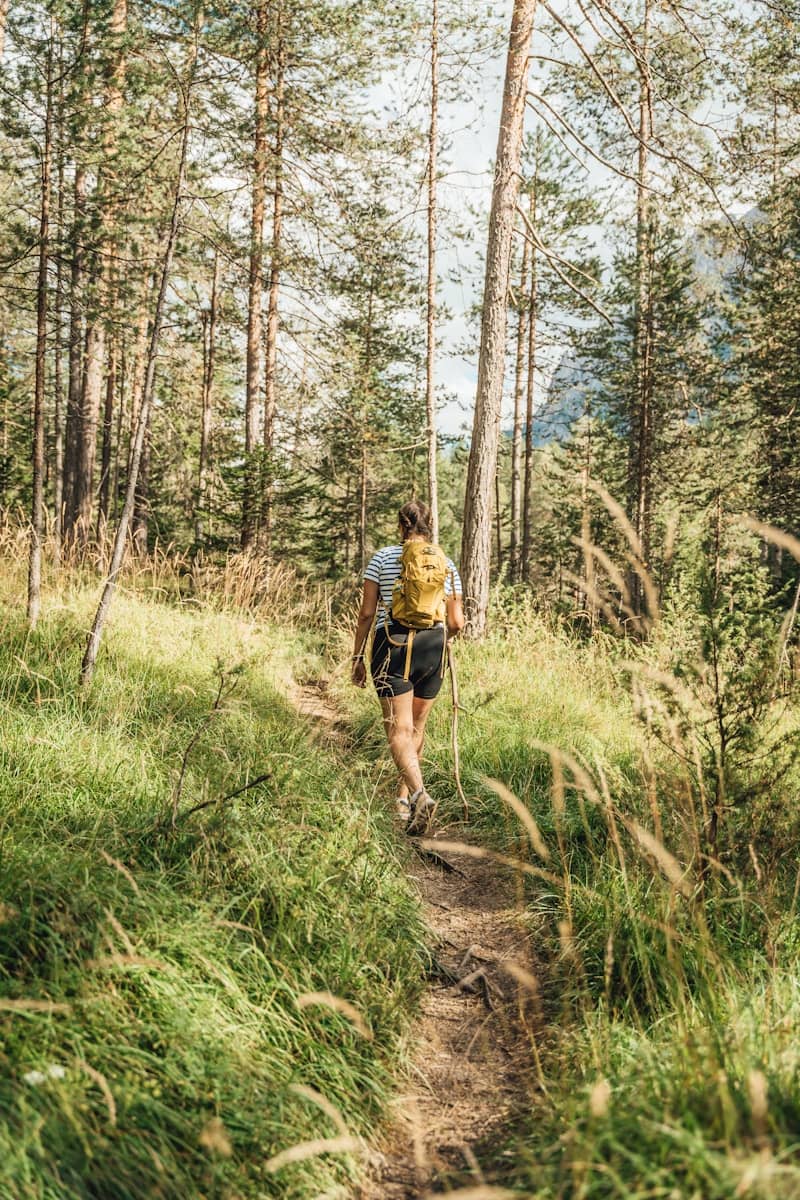 Person hiking on a forest path with backpack.