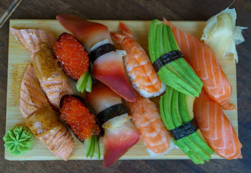 Assorted sushi pieces with salmon, shrimp, avocado, and roe on a wooden board