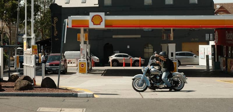 Man rides motorcycle at a shell gas station.