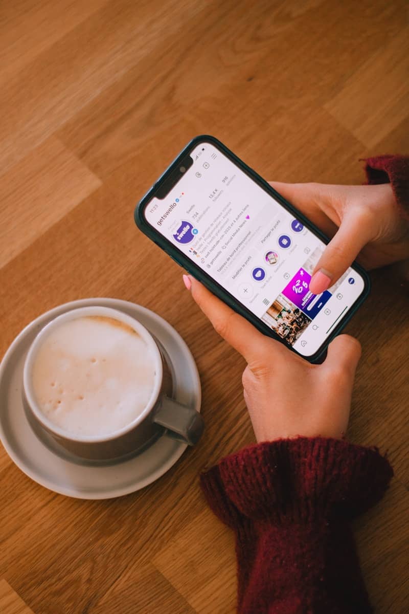 Person uses phone near a coffee cup.