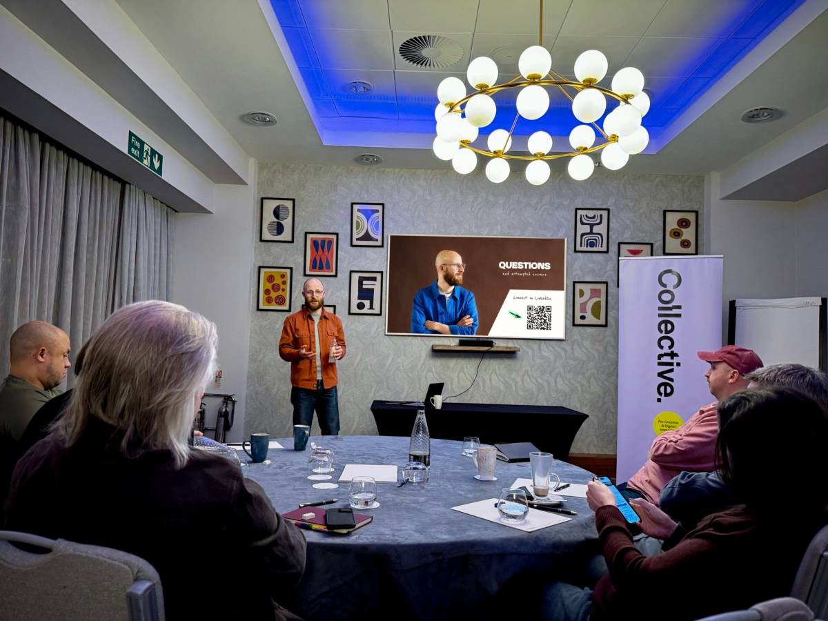 Kevin Karaca giving a talk on brand storytelling. Kevin's stood in a conference room with a TV behind him.