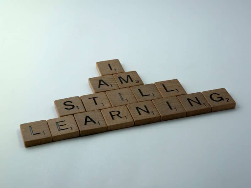 Scrabble tiles in a pyramid that say "I am still learning"