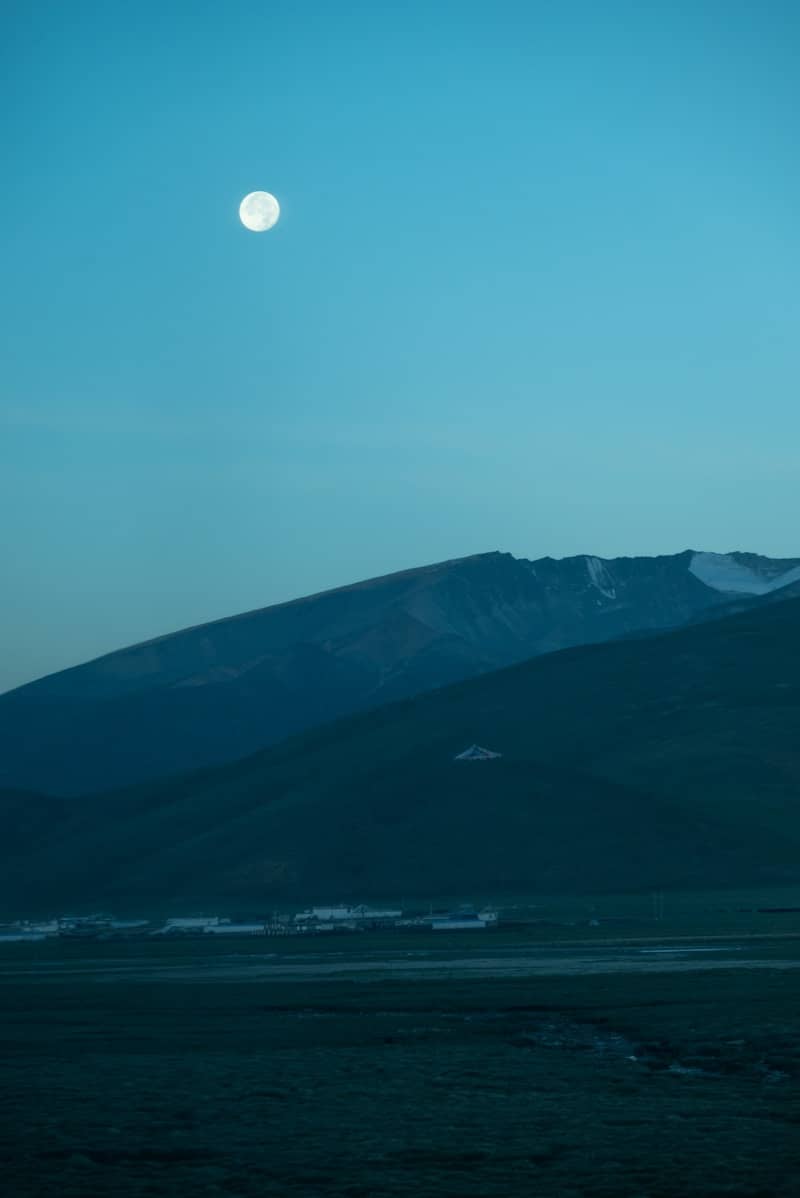 Full moon over dark mountains and valley.