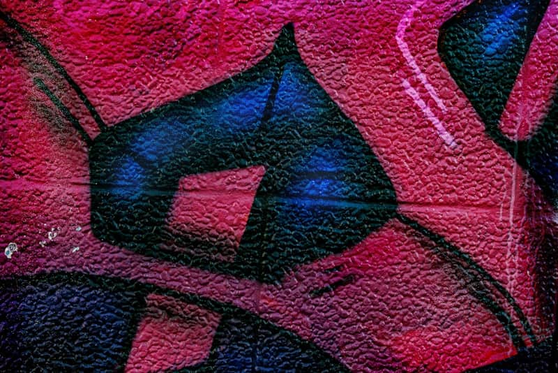 Abstract graffiti art with pink, blue, and black colors.