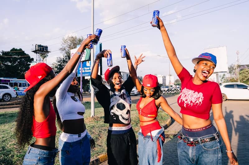 Five friends raise cans in celebration outdoors