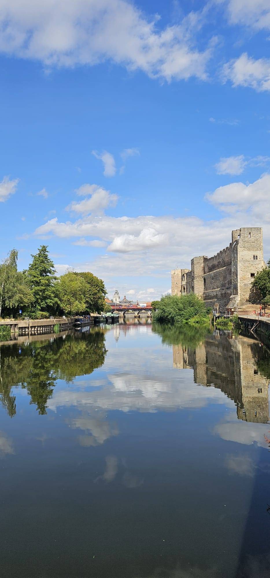 newark castle, on the canal under a cloudy sky with the castle reflected in the canal water
