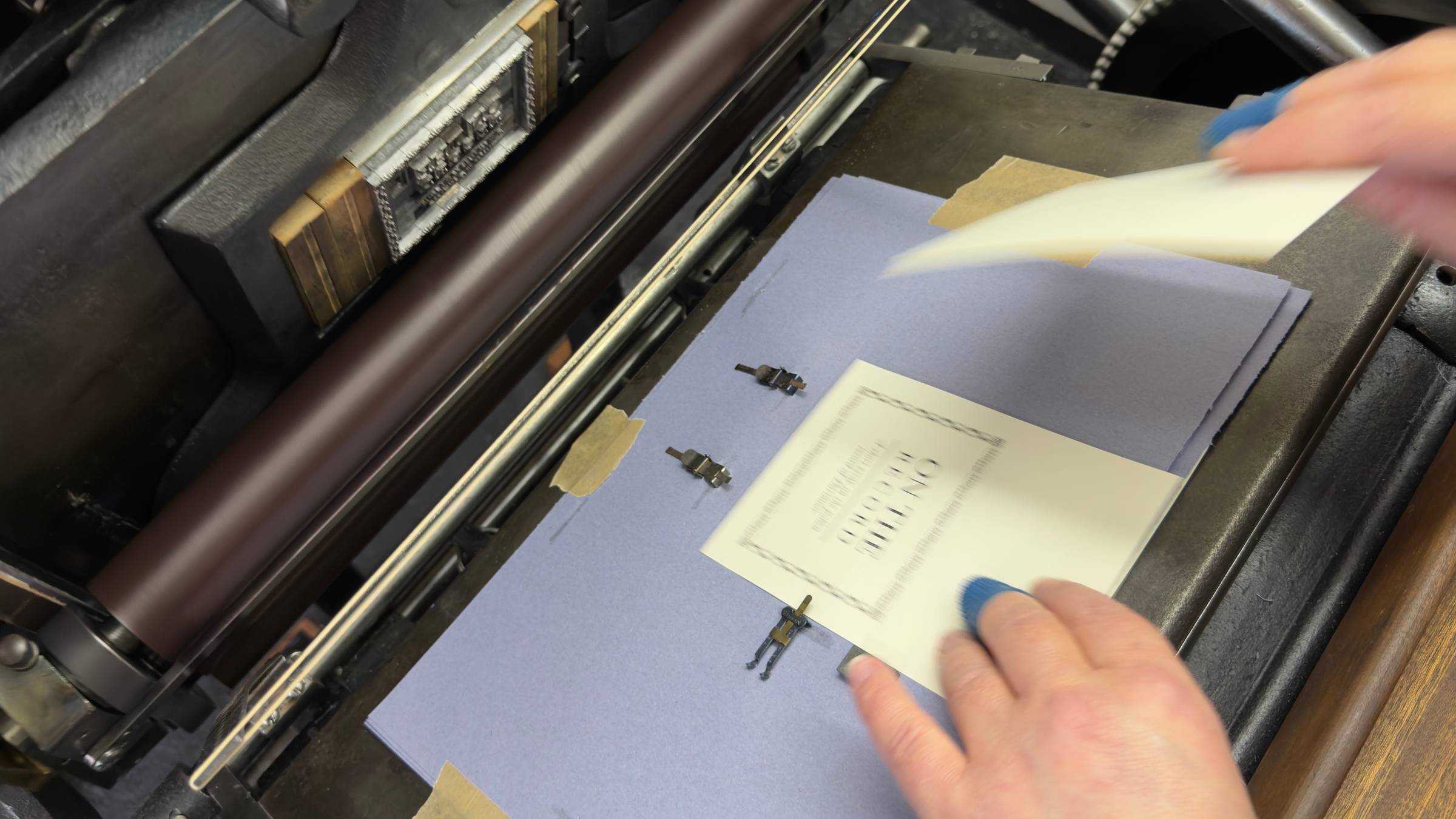 Hands switching sheets of paper on an old fashioned printing press