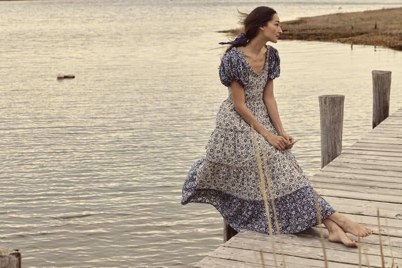 Woman wearing Doen floral print dress on a dock