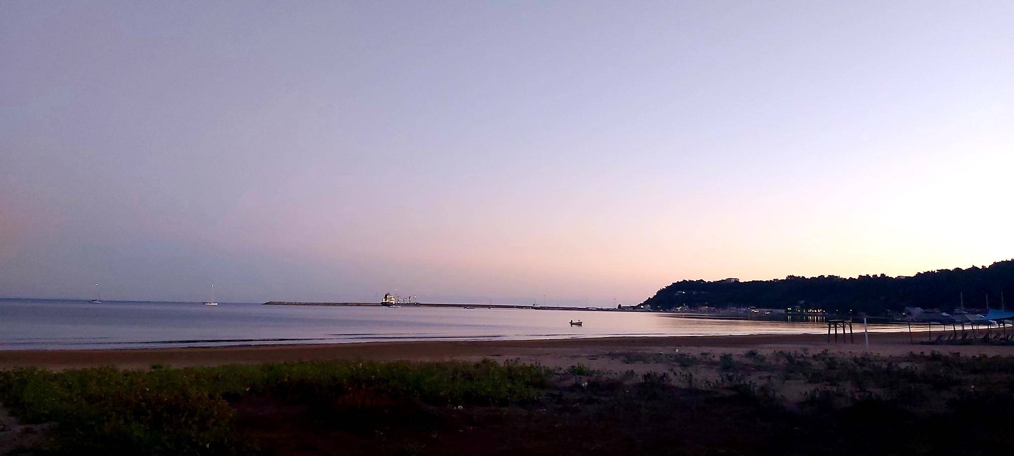 a calm sea in a beautiful bay at sunset in subdued tones of lilac and lavender
