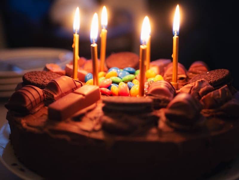 Birthday cake with lit candles and candy.