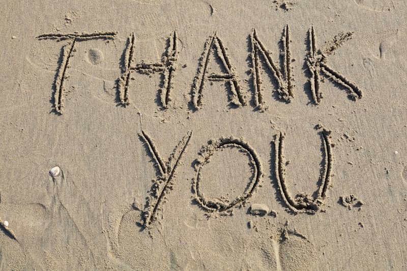 Thank you is written on the sand.