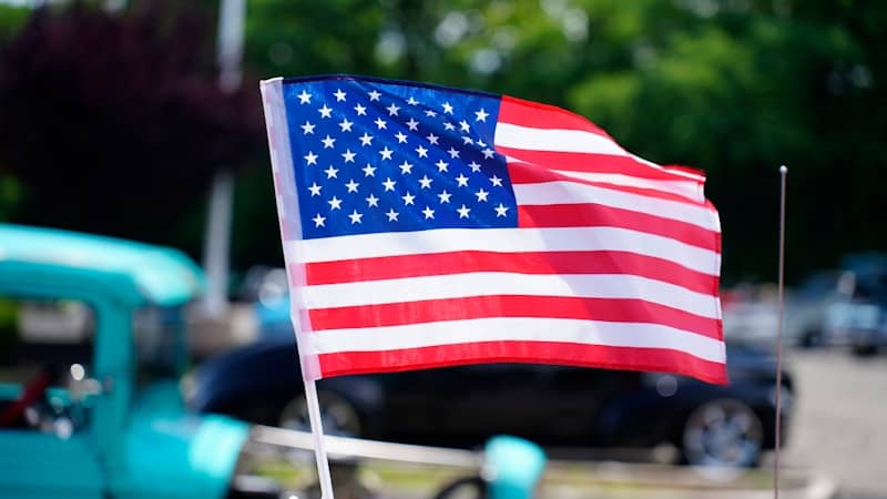 American flag waving in the breeze with cars.