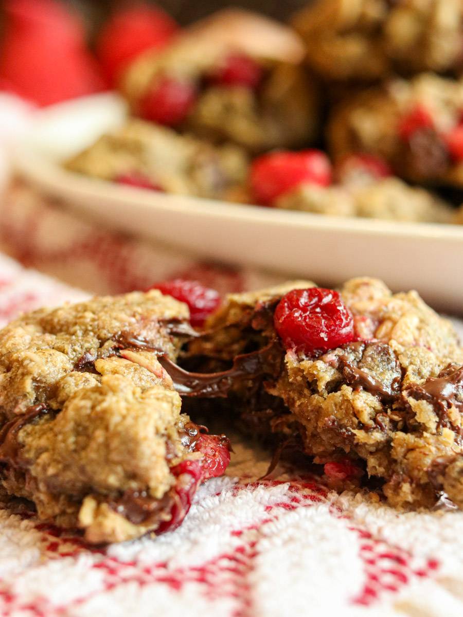 A cranberry chocolate chip oatmeal cookie split in half showing gooey chocolate.
