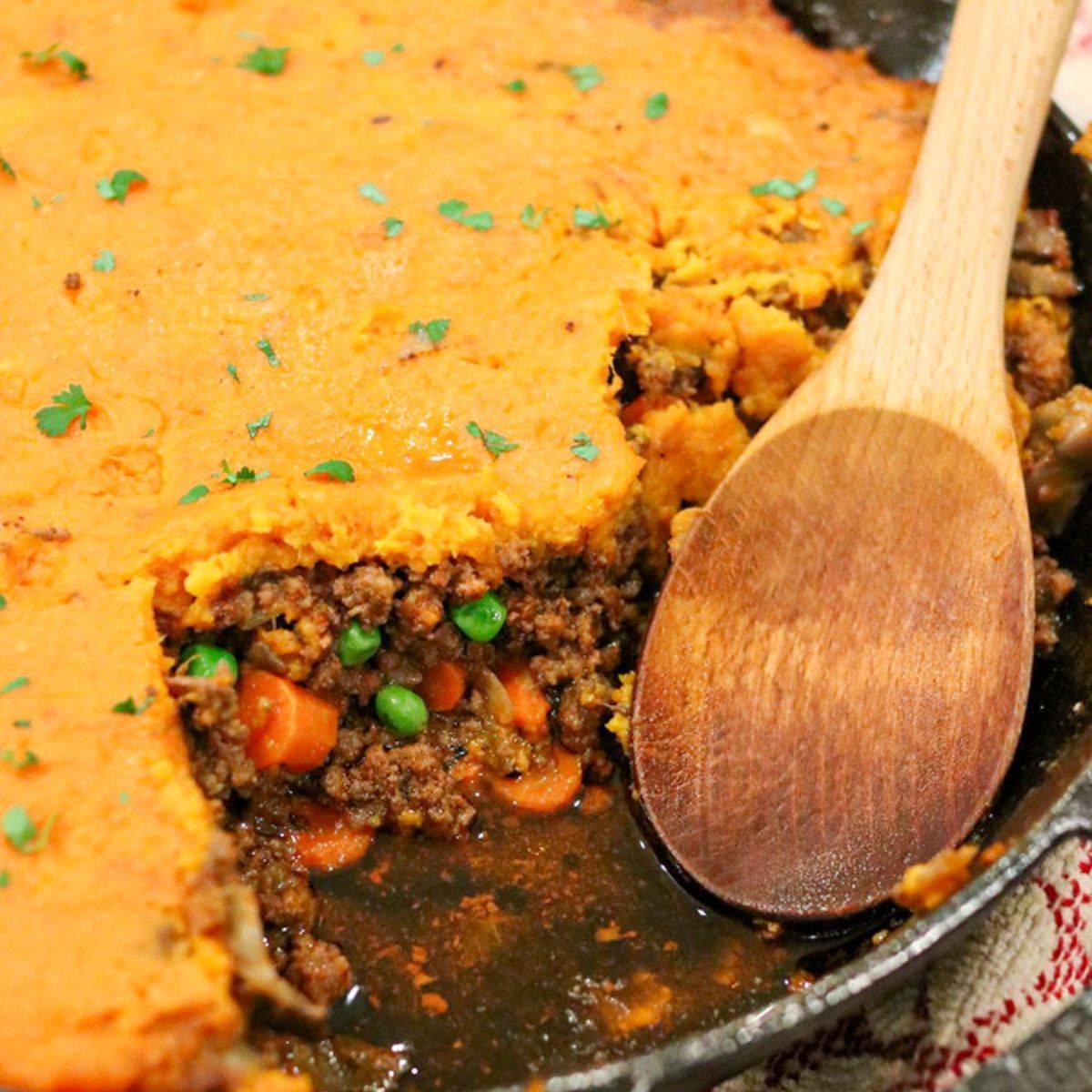 Sweet potato cottage pie with a scoop taken out showing the beef and vegetable filling.