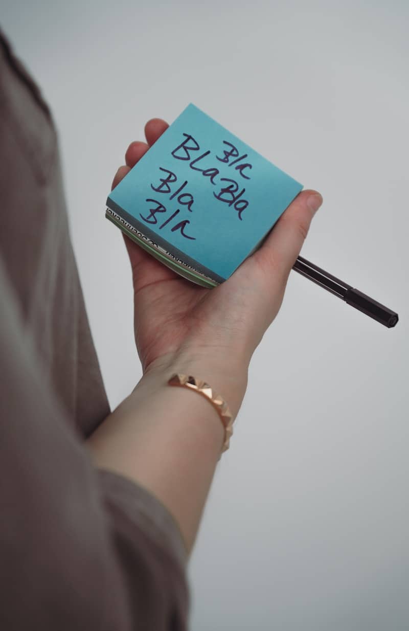 A person holding a pen and a sticky note