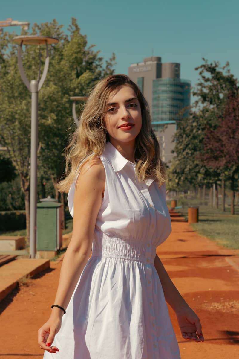 A woman in a white dress standing on a sidewalk