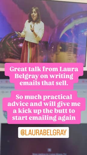 Laura Belgray stands on stage holding a microphone, wearing a white top and a long skirt with red, pink, and yellow vertical stripes. Behind her is a colorful, abstract background with large reflective balloons. Overlaid pink text reads: "Great talk from Laura Belgray on writing emails that sell. So much practical advice and will give me a kick up the butt to start emailing again." The Instagram handle @LAURABELGRAY appears at the bottom.