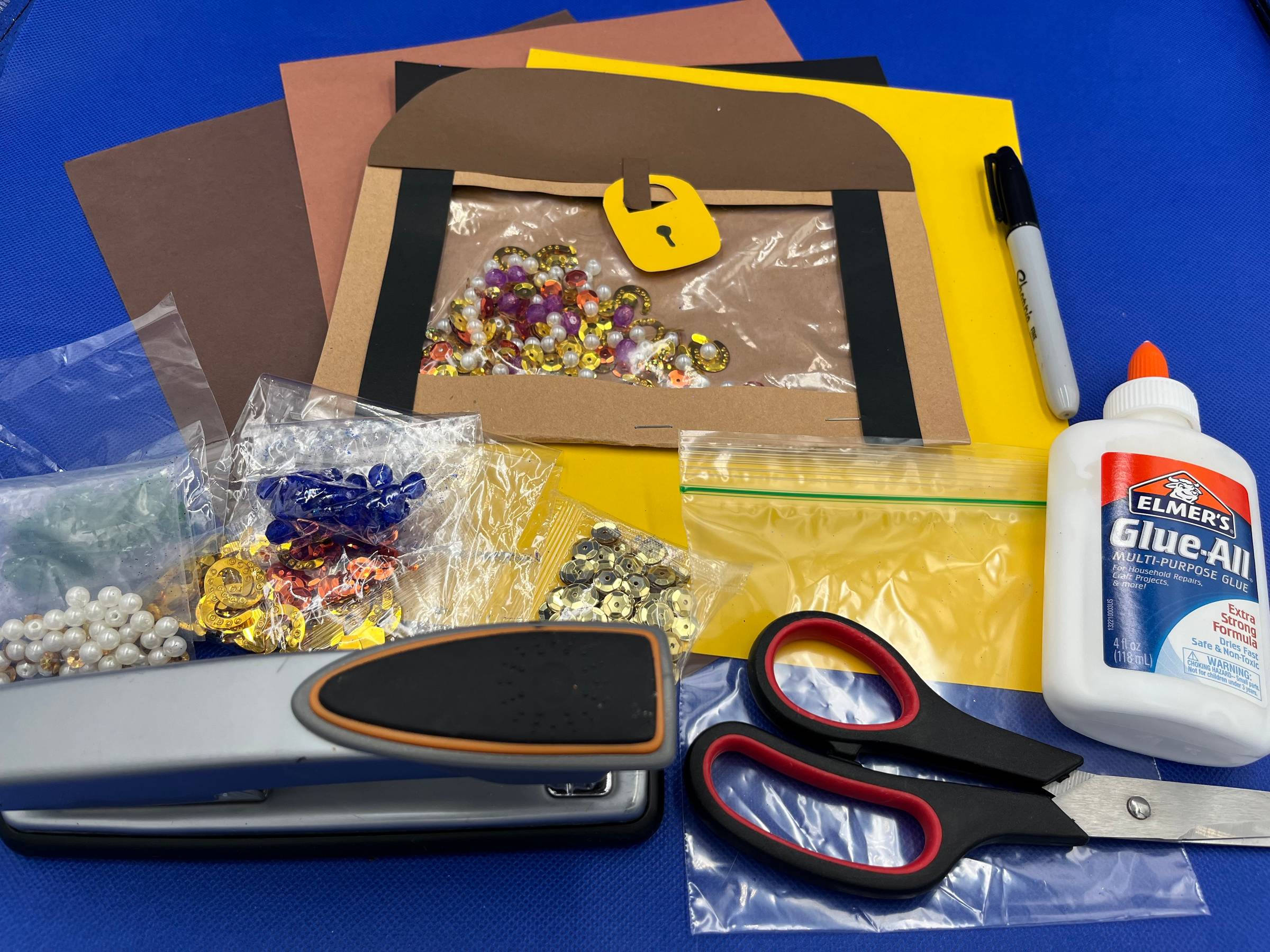 Paper and plastic bag treasure chest and the supplies needed to make your own.