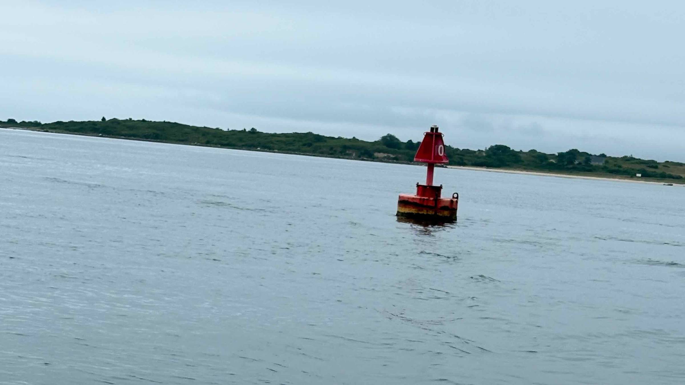 Red marker "0" at the Buzzards Bay entrance to Wood's Hole on a calm, overcast summer day.