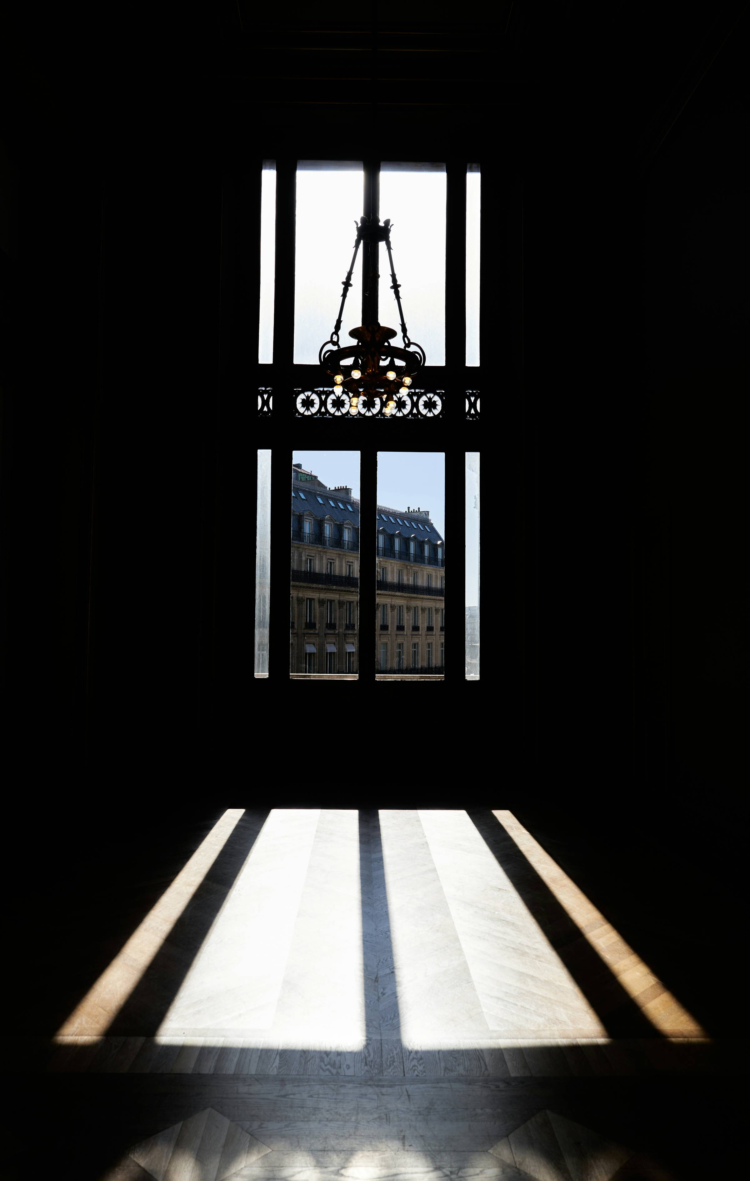 Light and shadow through an ornate Paris doorway, looking toward the buildings beyond.