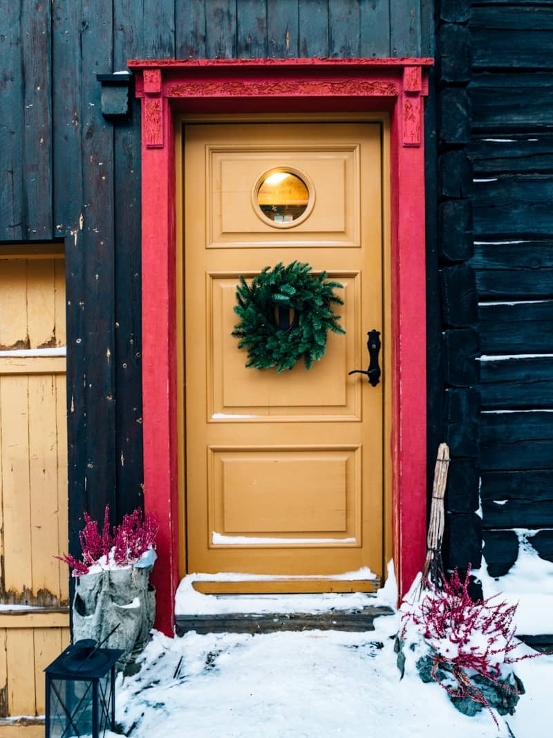 Yellow door with wreath in snowy setting