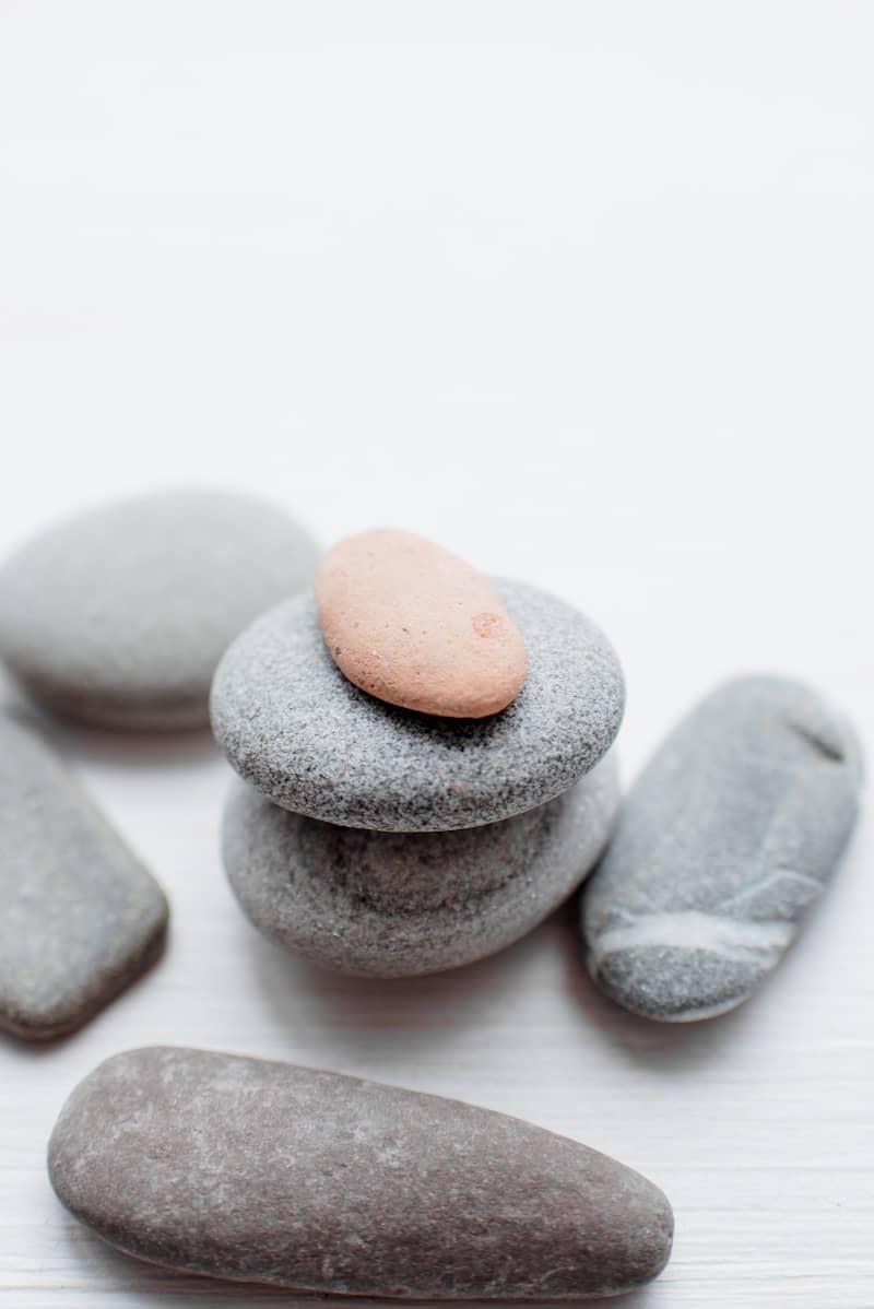 Smooth grey and pink stones stacked on a white surface.