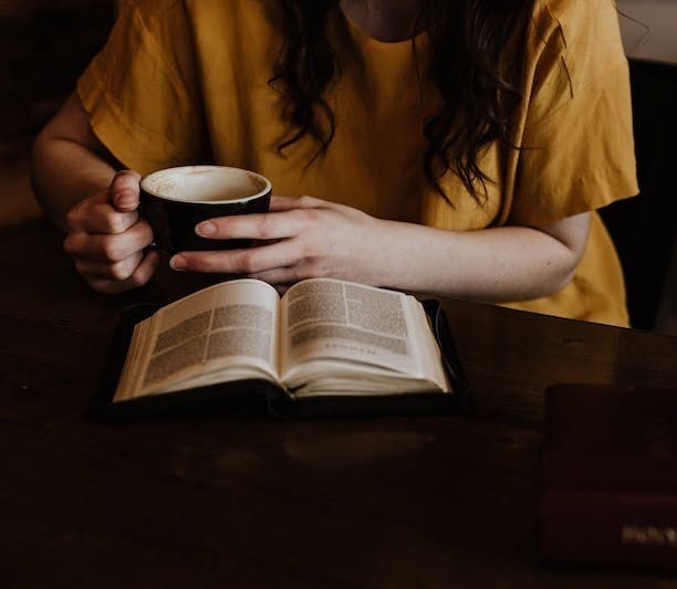 woman holding mug in front of book