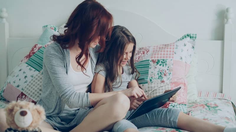 Mom and daughter read on a tablet together.