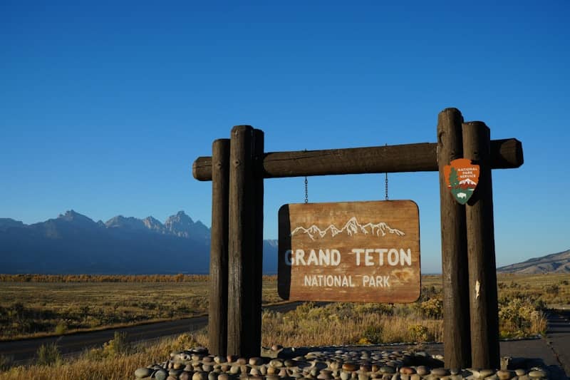 A sign for grand teton national park with mountains in the background