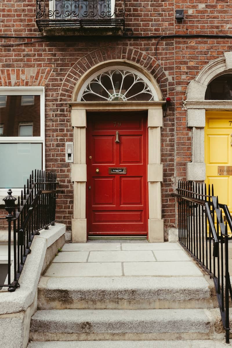 Red door with stone steps and a decorative fanlight.