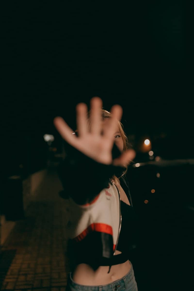 Woman is holding up her hand in the night.