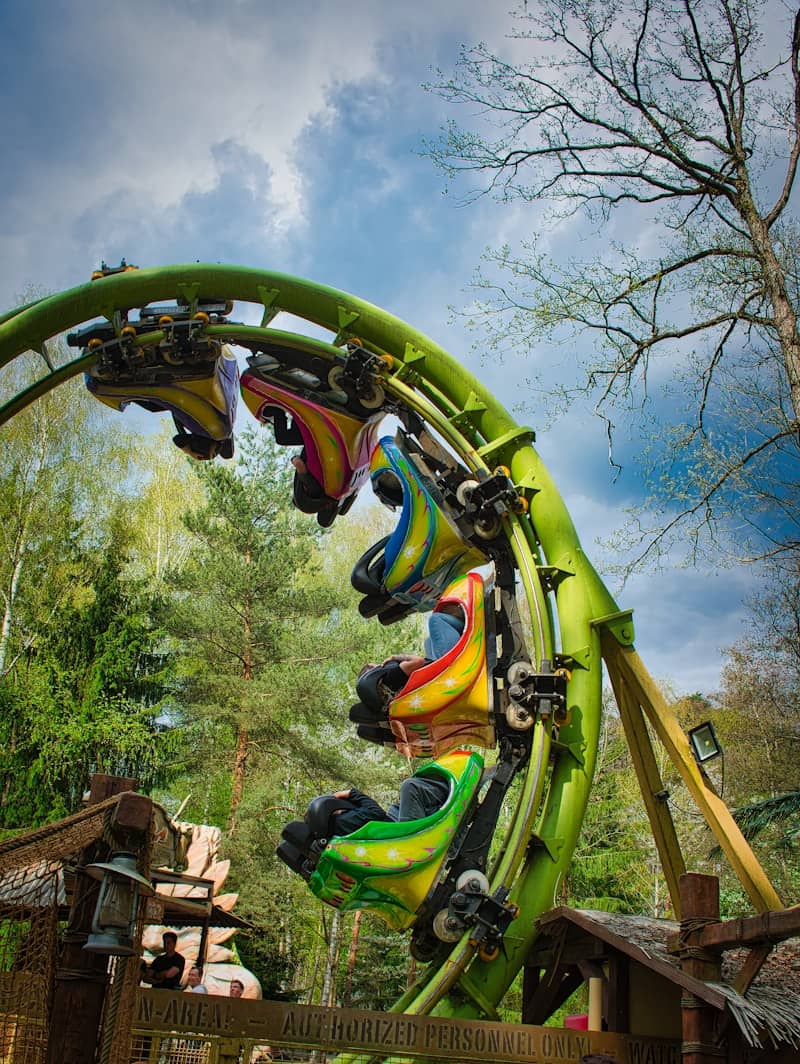 Roller coaster cars ascend a green track loop.