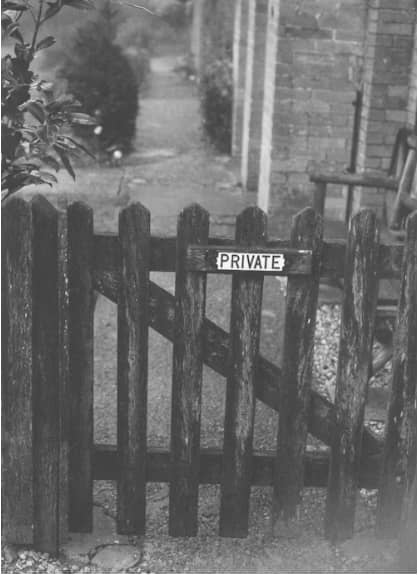 black and white picture of a fence with a sign that reads "private"