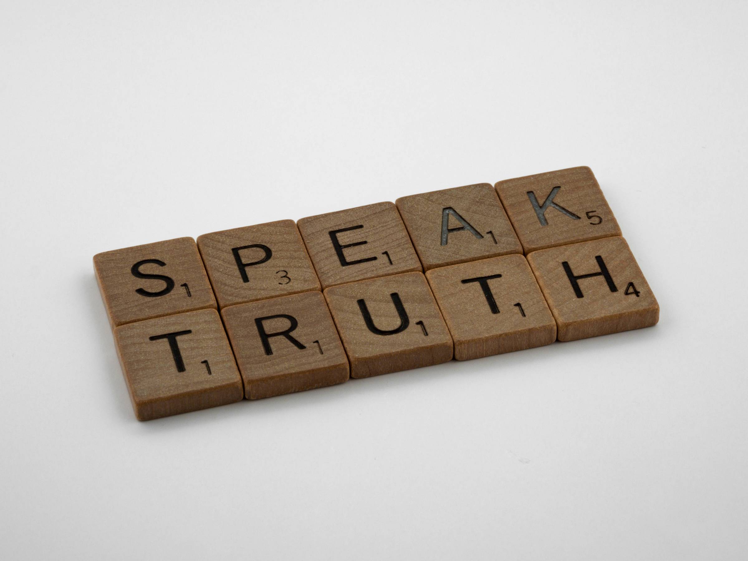 brown wooden blocks on a white background that form the words "speak truth"