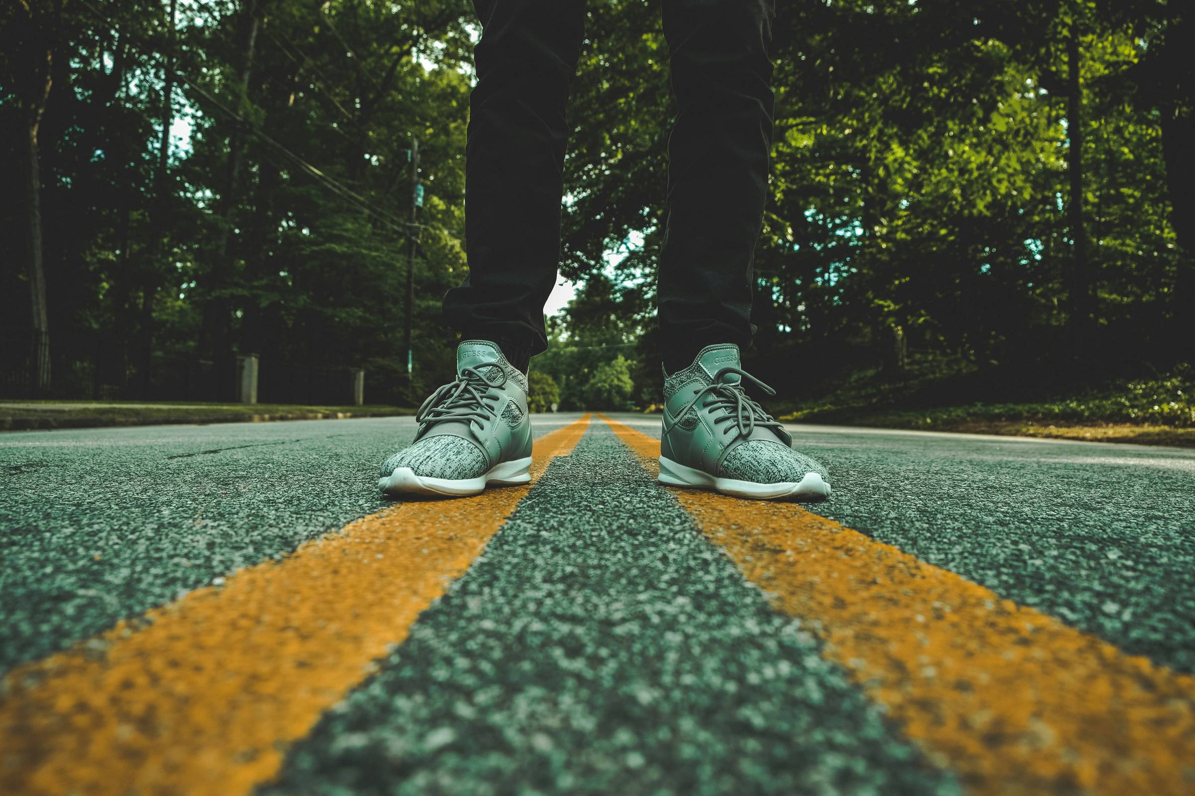 person standing on concrete road between traffic lines