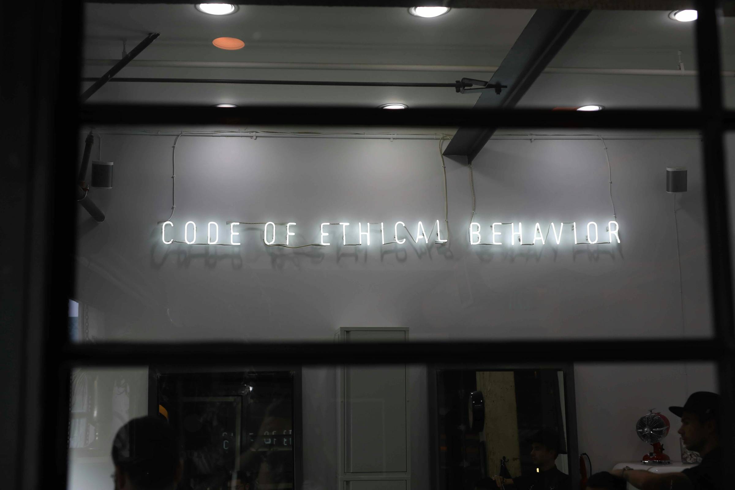 black and white picture of a shop front that reads code of ethical behaviour in fluorescent lights