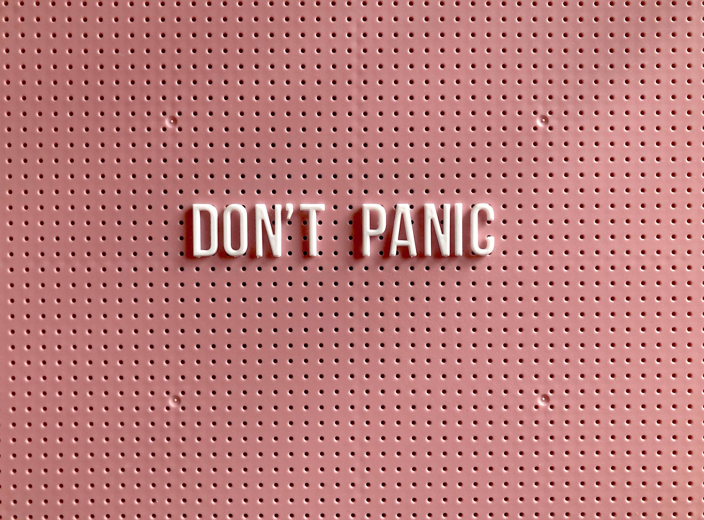 text that reads "don't panic" on pink board