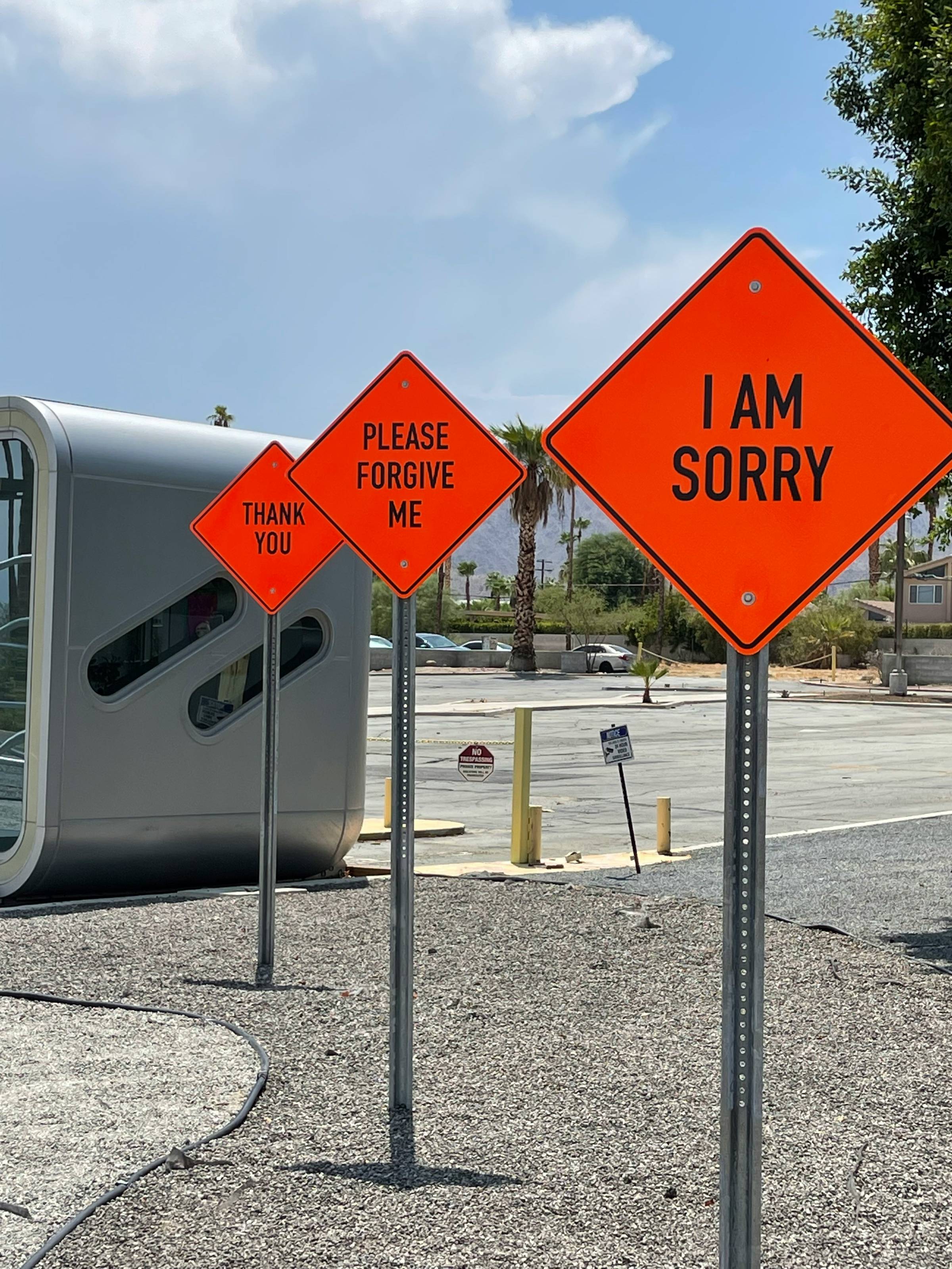 three red road signs that read "I am sorry", "please forgive me", "thank you"