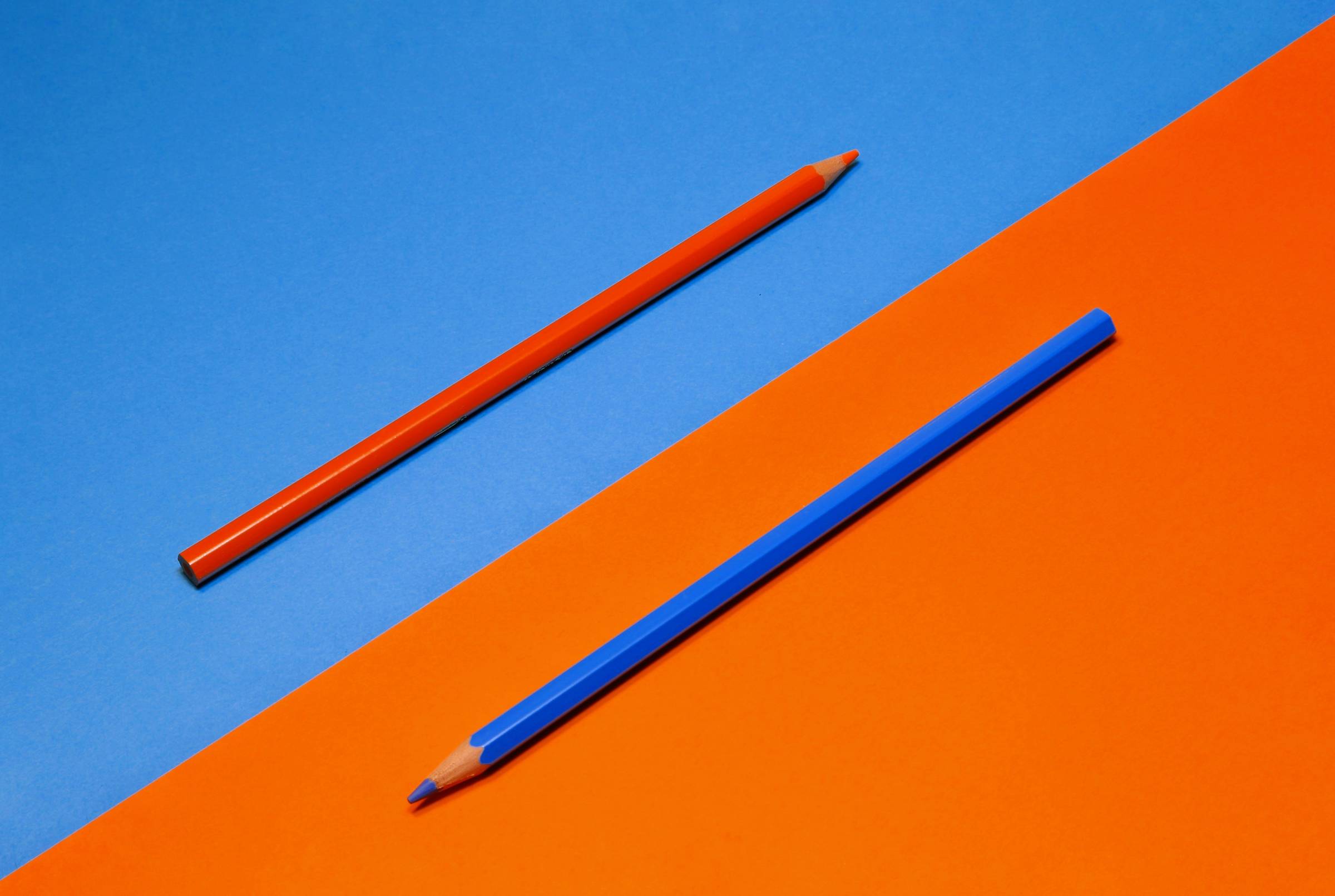 blue pencil on orange background and orange pencil on blue background