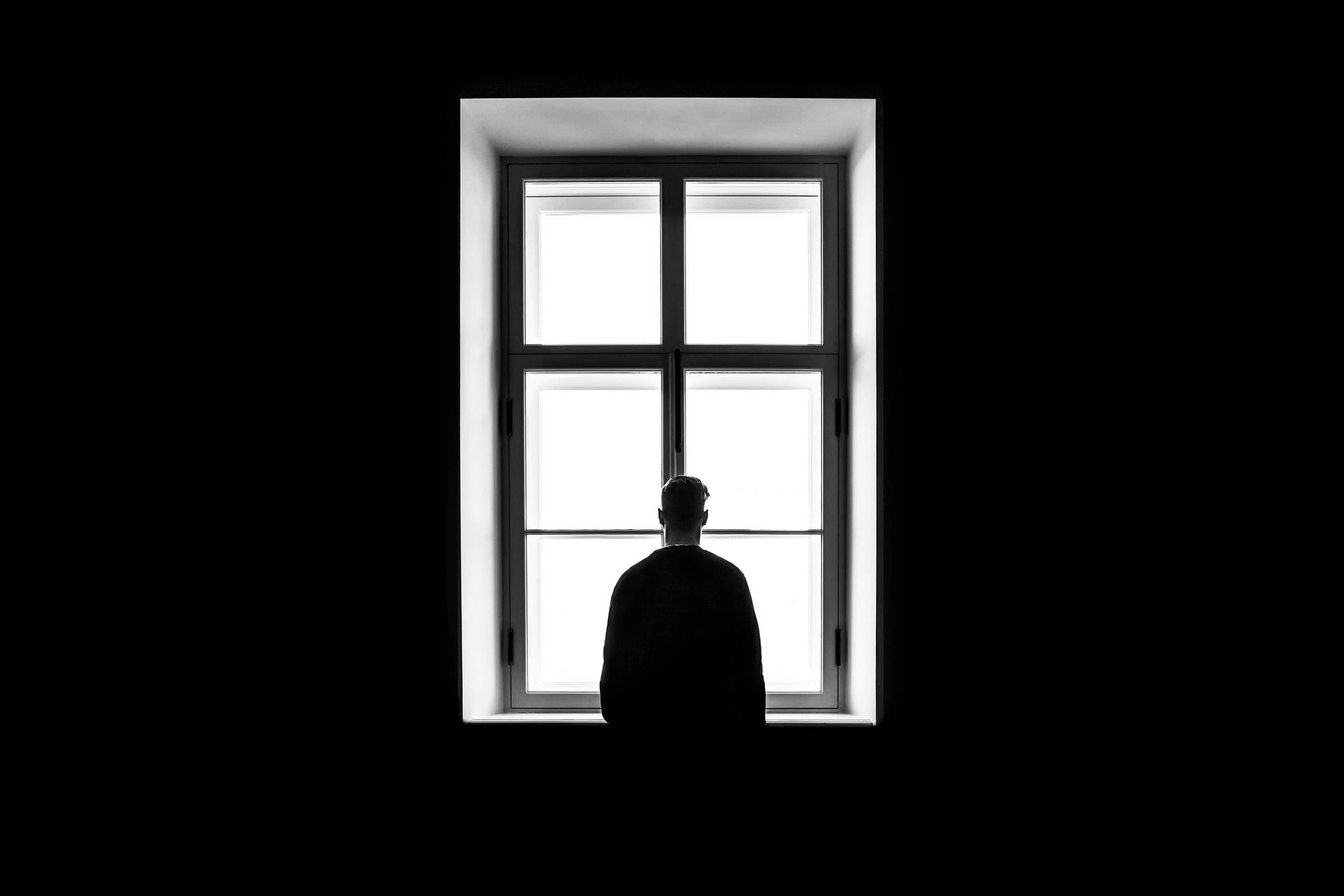black and white picture of a person looking through a window