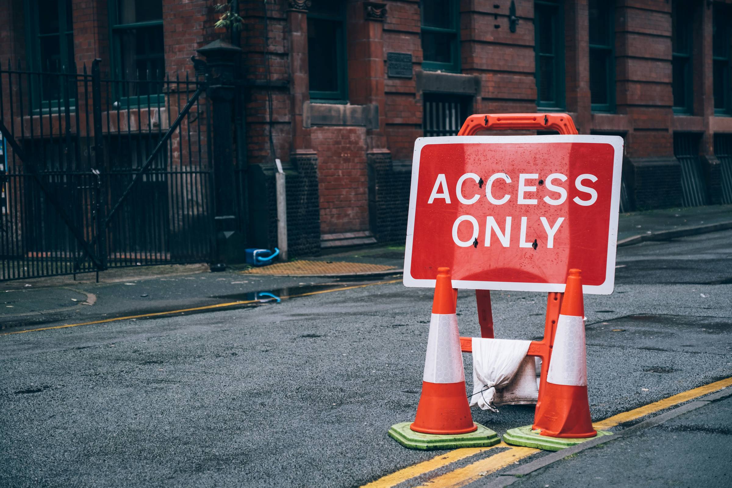 two traffic cones and red banner that reads "access only"