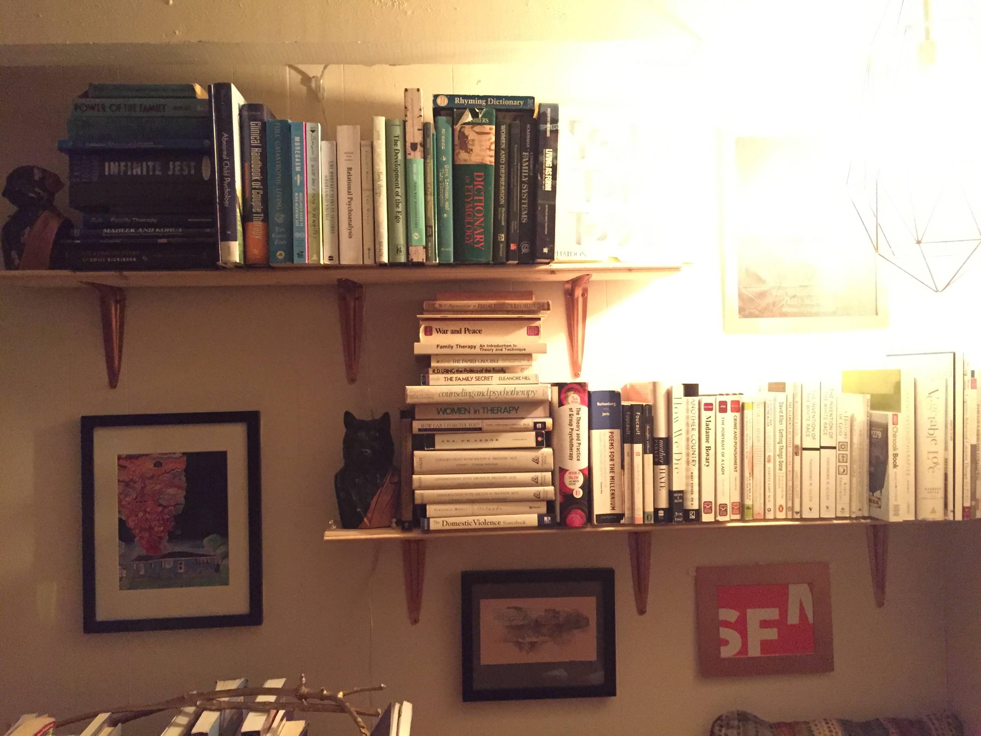 pictures and bookshelves full of books on a white wall with a bright light shining on the top right corner