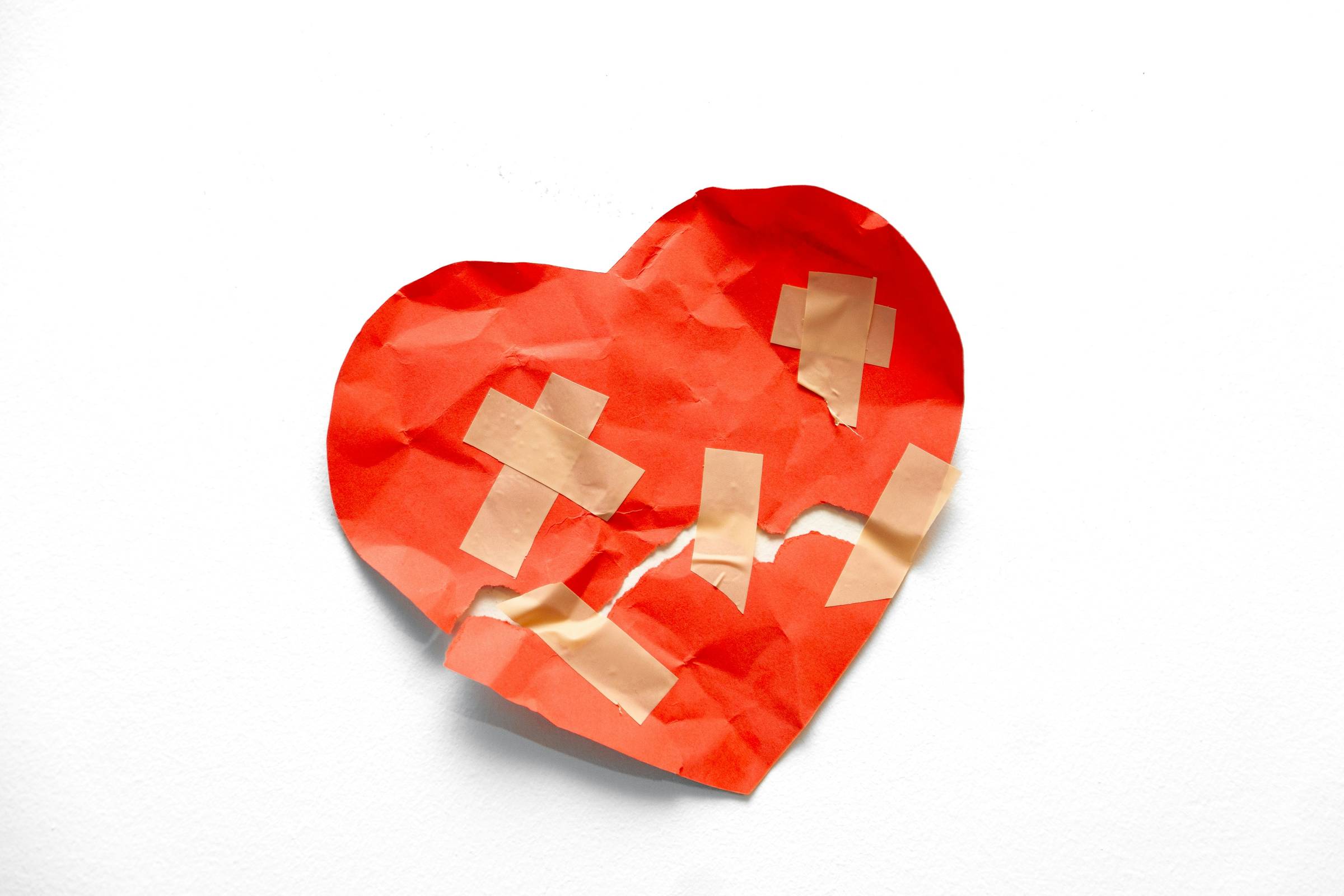 red mended paper heart on white background