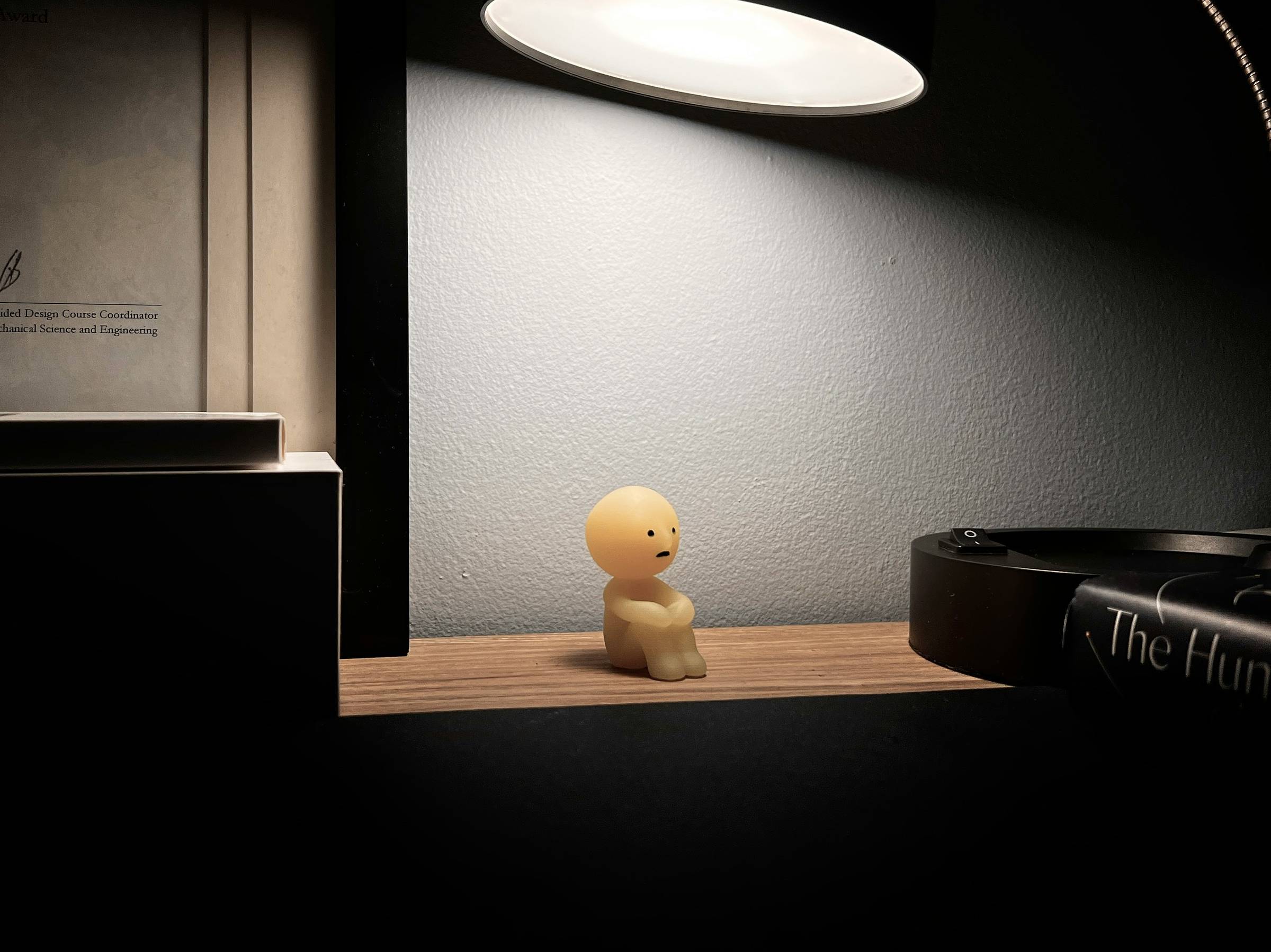 small human shaped toy sitting on a wooden table