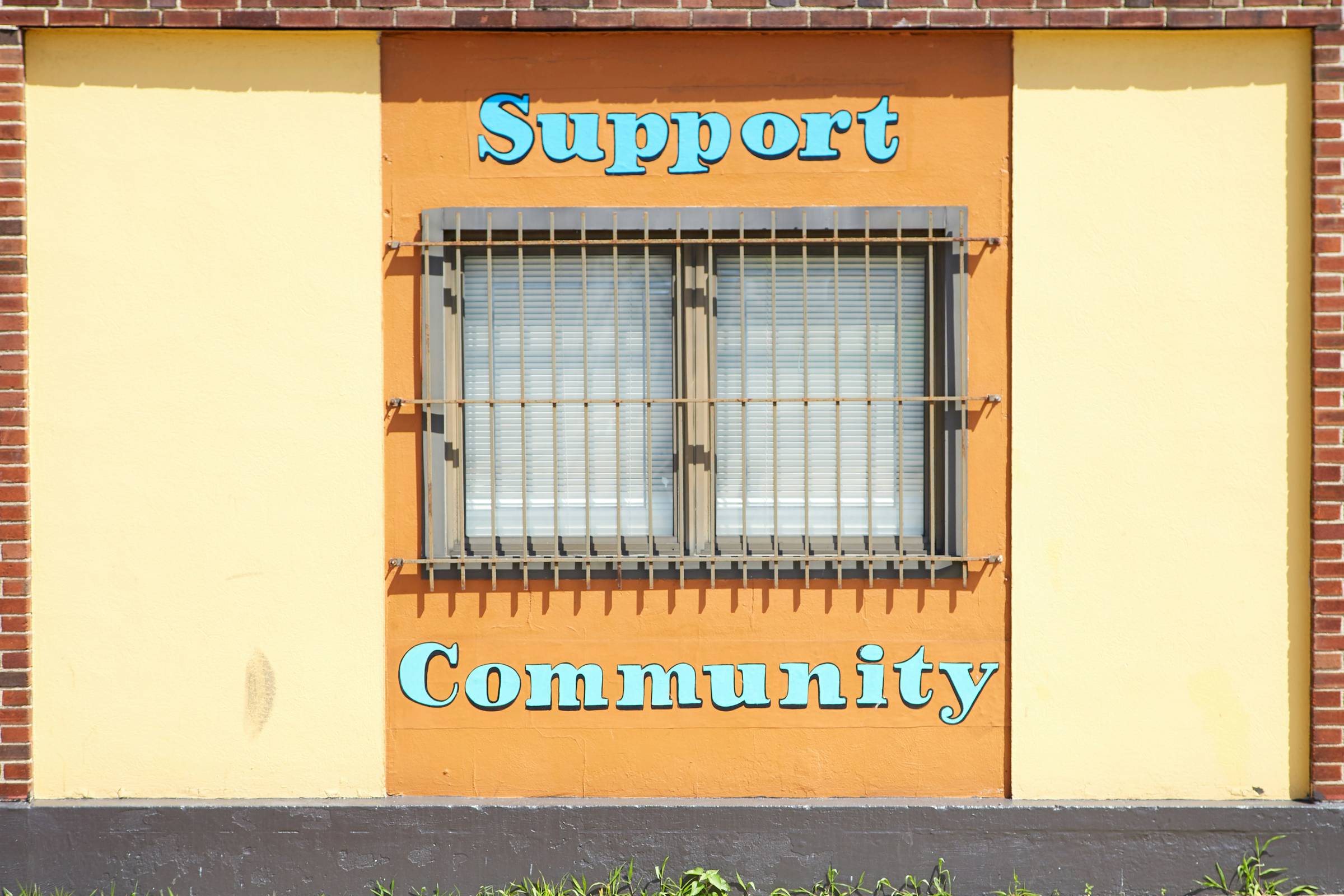 brown steel window frame with text on top and bottom that reads "support, community"