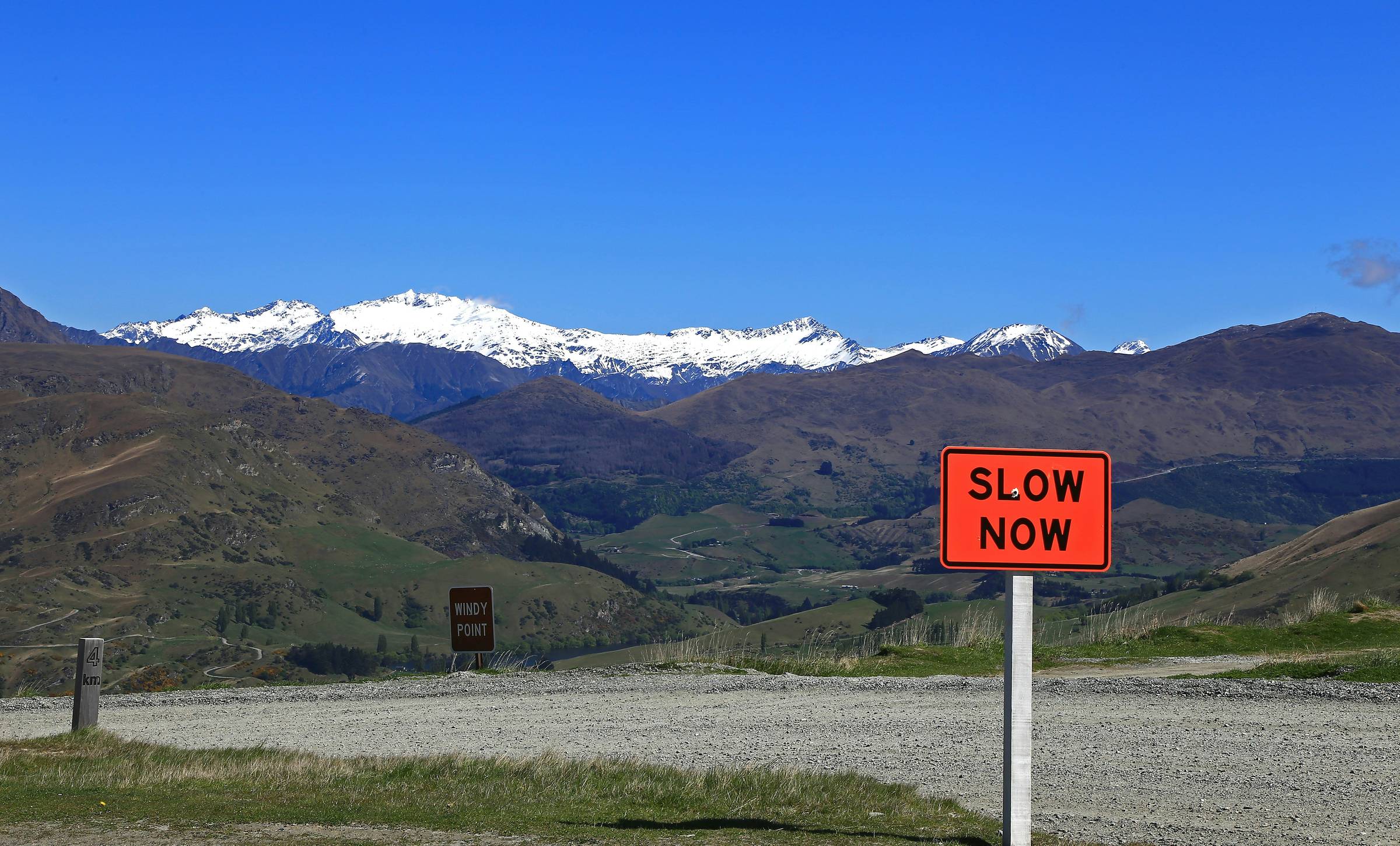 red slow down signage with snow mountains in the background