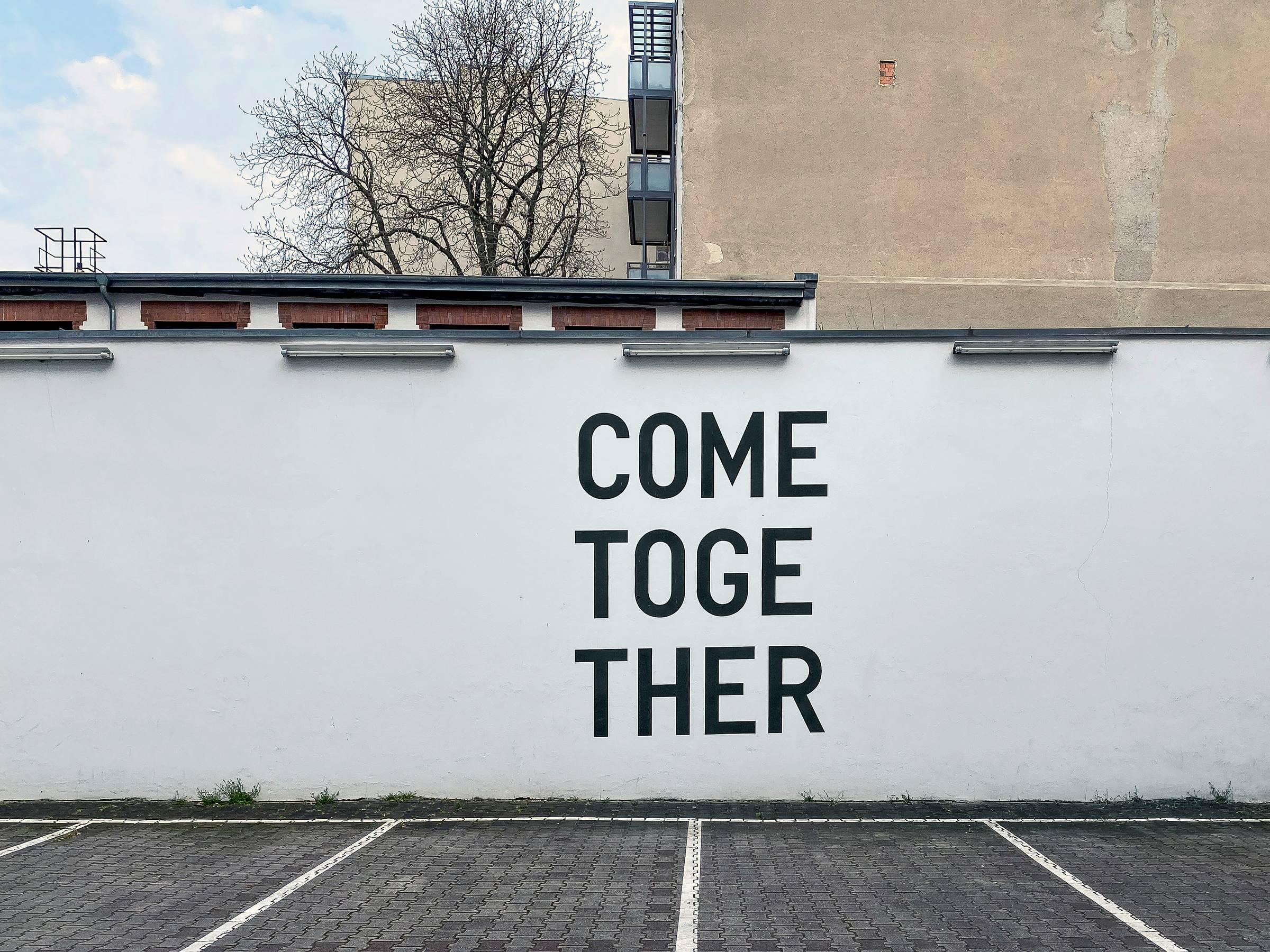 large white wall with the words "come together" on it in black