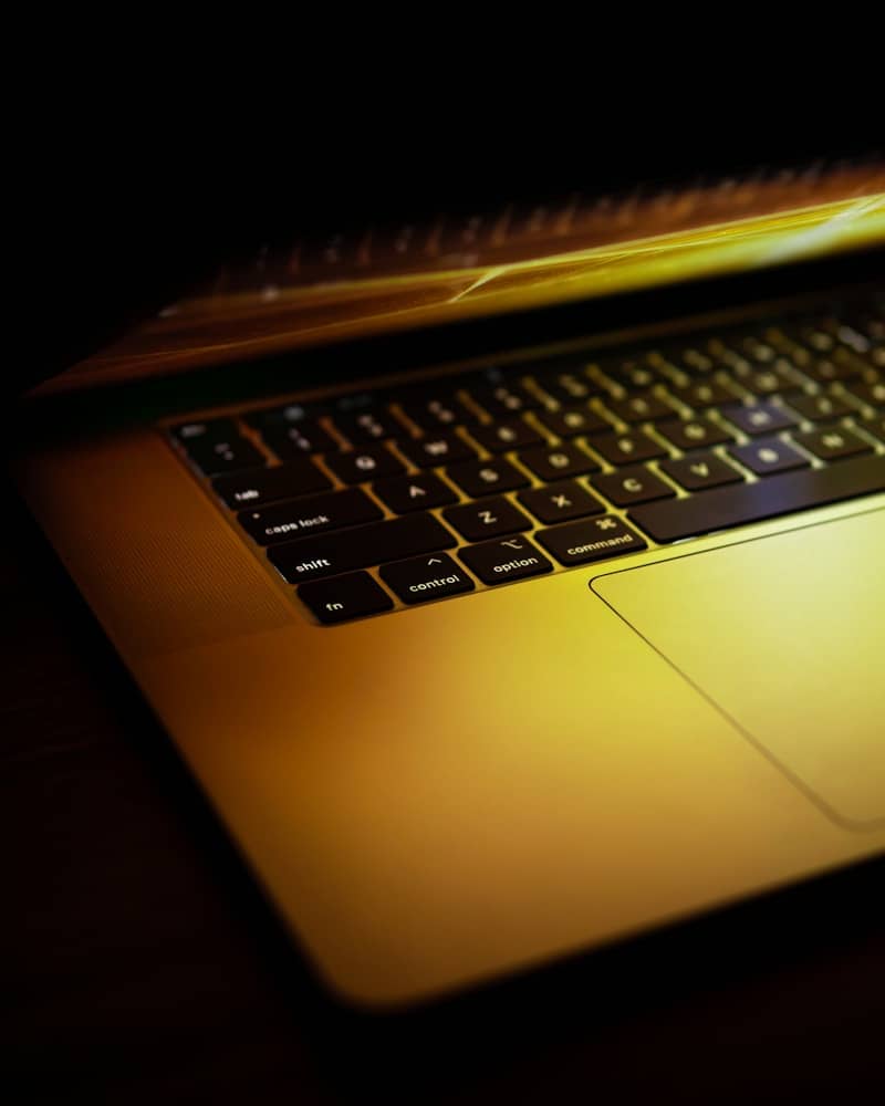 Golden light from a laptop screen illuminates its keyboard.
