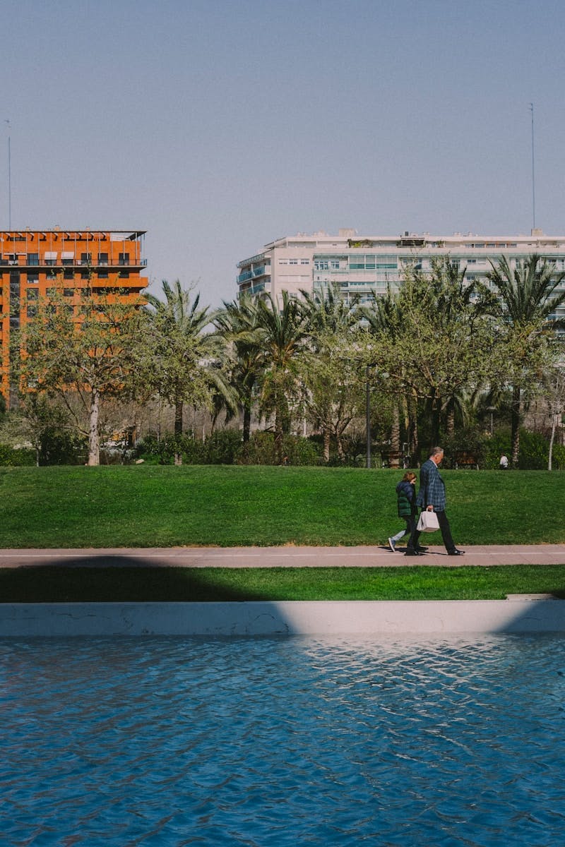 man in black jacket standing on green grass field near body of water during daytime