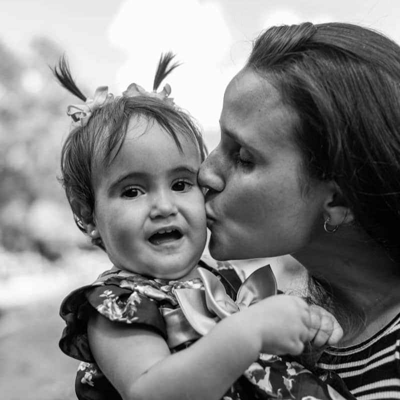 Mother kisses her baby daughter in black and white.